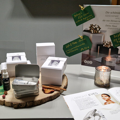 Verschiedene Kosmetikprodukte und Flyer auf einem Holztisch dekorativ arrangiert